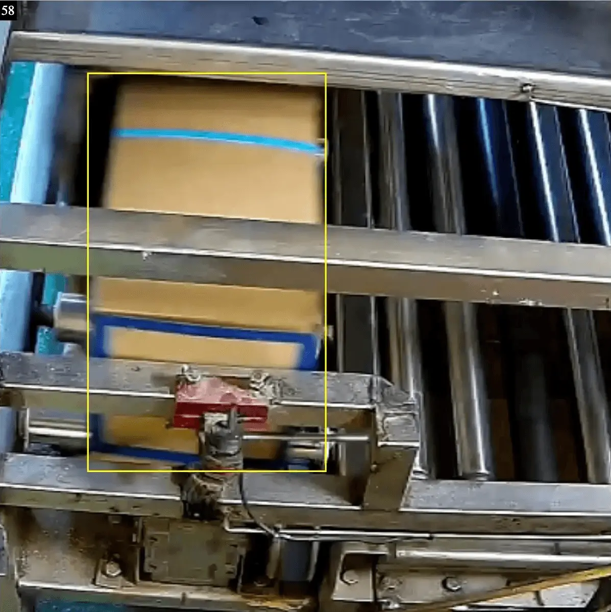 Box of frozen fish marked with a yellow detection frame on a trawler conveyor filmed by a colour camera